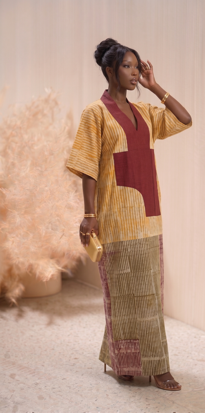 Woman wearing a colorful Adire outfit with a patterned skirt and top against a neutral background