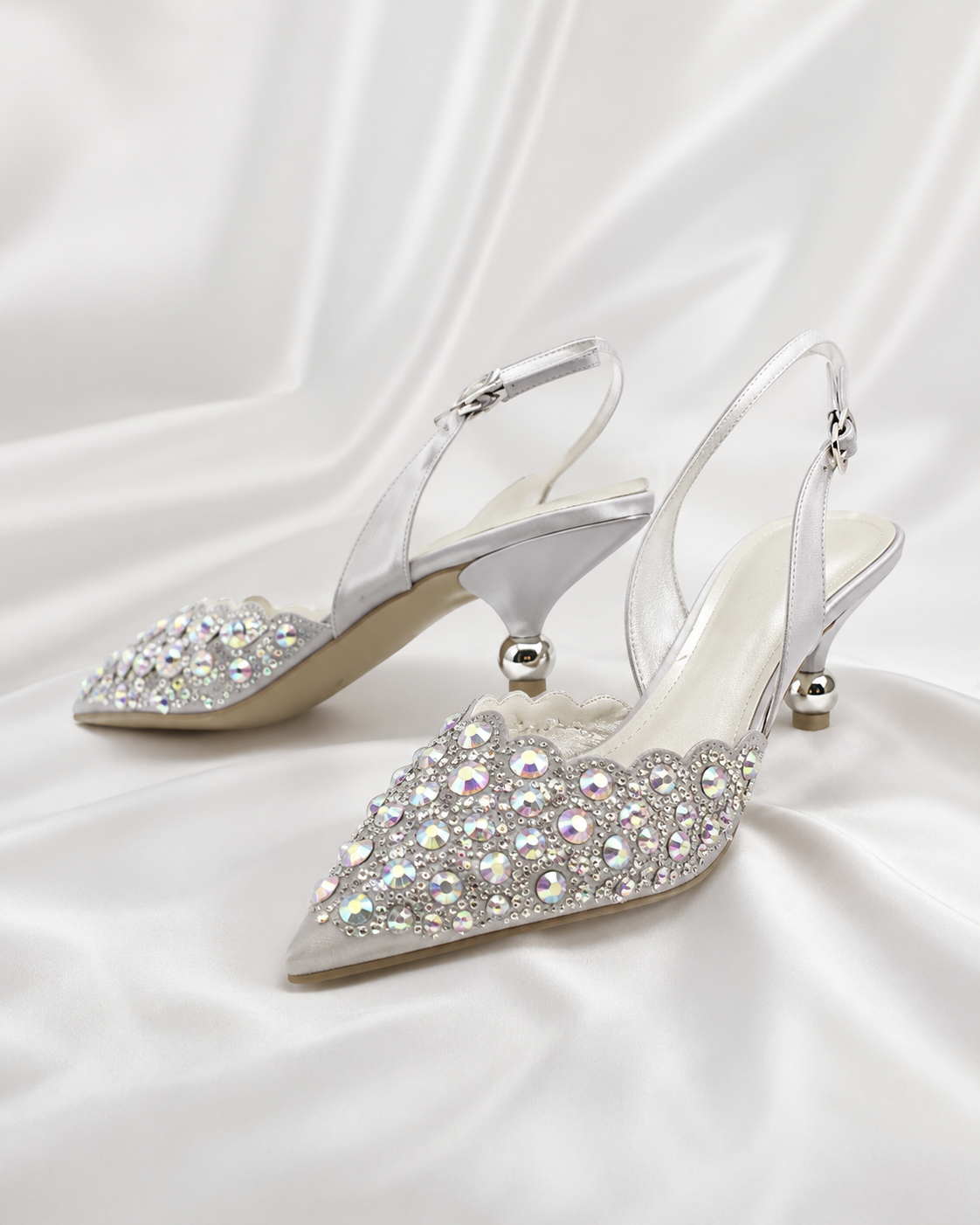 A pair of pointed-toe slingback high heels embellished with sparkling silver and iridescent rhinestones.