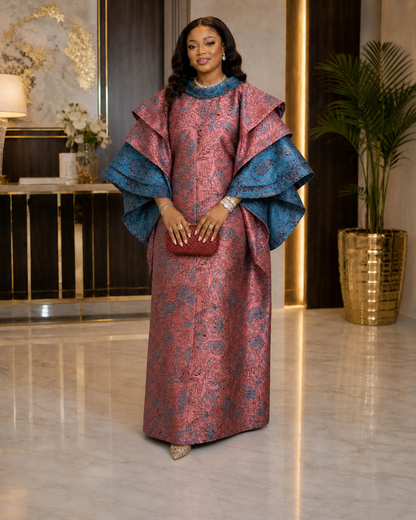A luxurious rose-pink and teal African boubou featuring ornate pattern detailing, dramatic layered sleeves, and a flowing maxi silhouette. Perfect for weddings, birthdays, church, Eid, owambe parties, and elegant cultural celebrations.